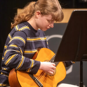 Student playing the acoustic guitar