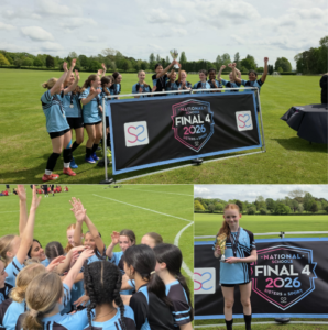 Girls’ soccer team in light-blue uniforms celebrates victory behind a banner reading Final 4 2026, holding a trophy on a sunny field.