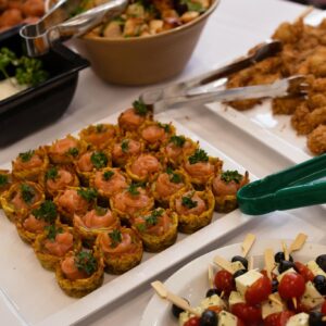 Tray of bite-sized salmon canapés topped with fresh dill and parsley on a white platter