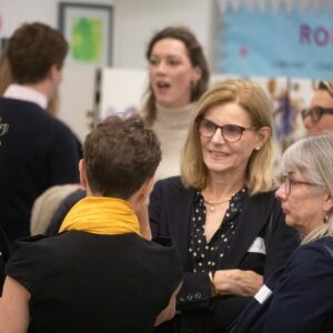 Group of adults in a social or networking event, conversing closely in a crowded room.