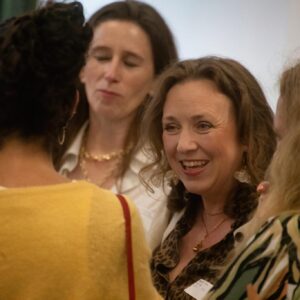 Smiling group of people in a social gathering, faces close together as they chat during a conversation.