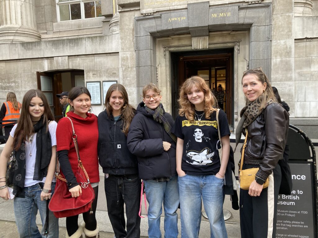 Six people posing for a photo outside a historic stone building with British Museum signage above the entrance.