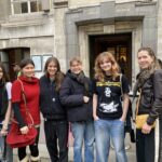 Six people posing for a photo outside a historic stone building with British Museum signage above the entrance.