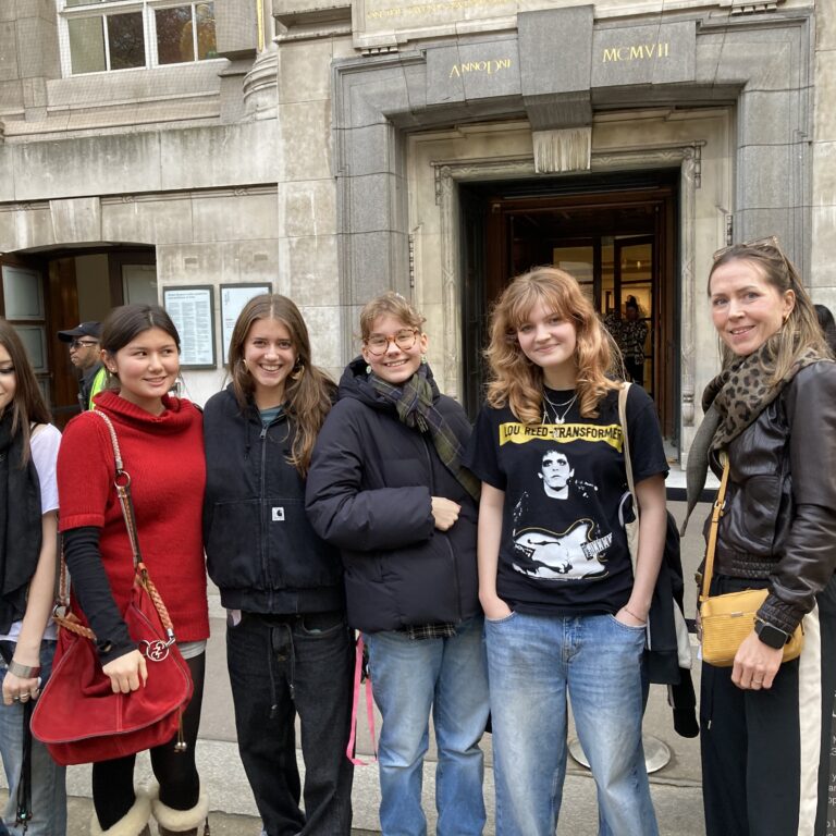 Six people posing for a photo outside a historic stone building with British Museum signage above the entrance.